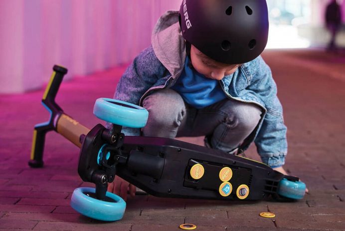 kid wearing a helmet, with a childs scooter